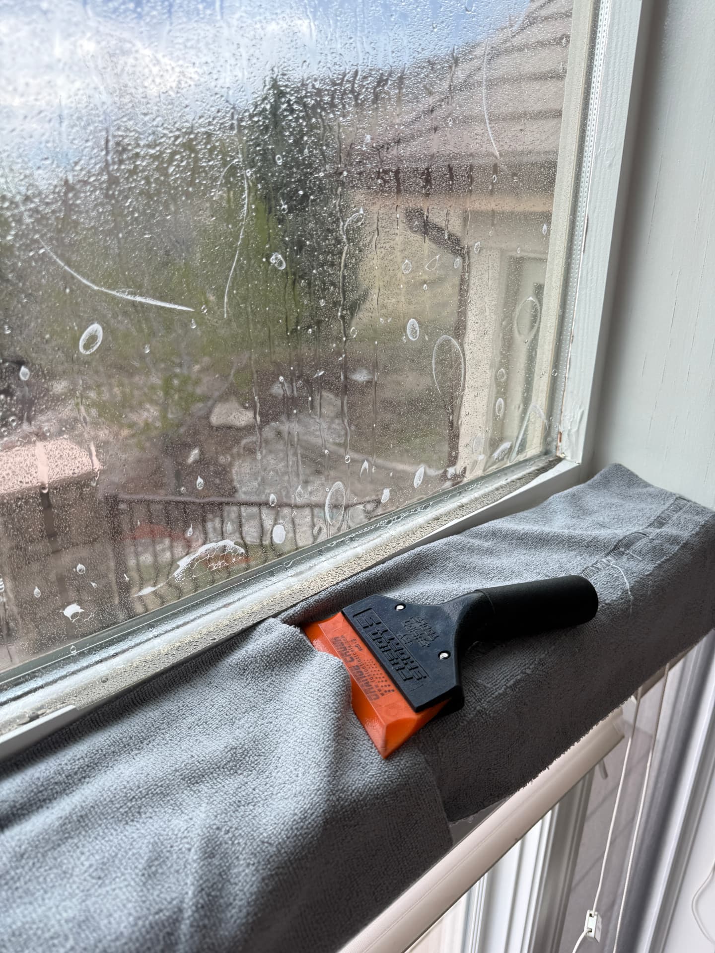 Close-up of a squeegee and freshly wet-applied window film on a residential window