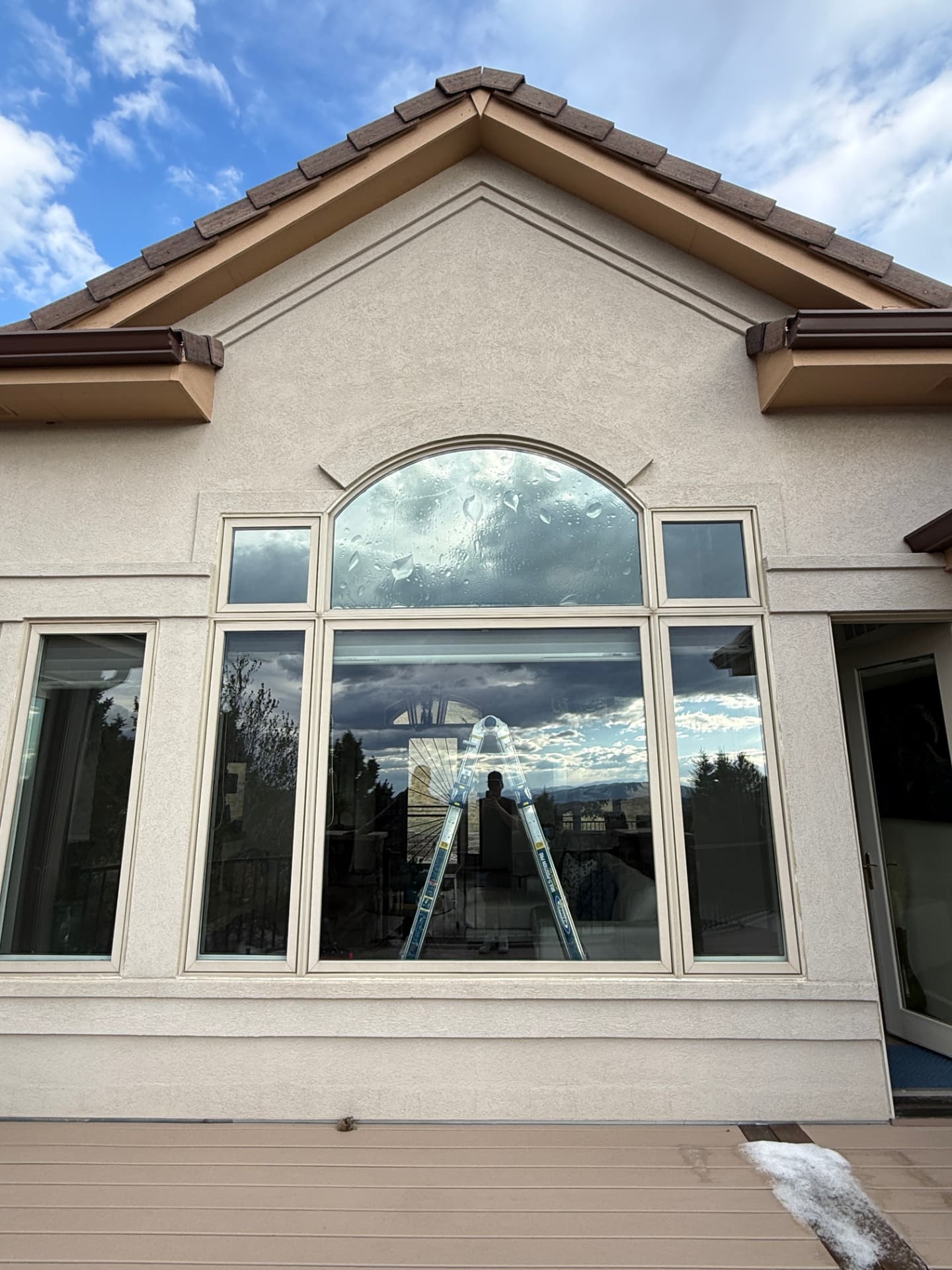 Large arched front-elevation window on a Castle Rock home during a residential window film install