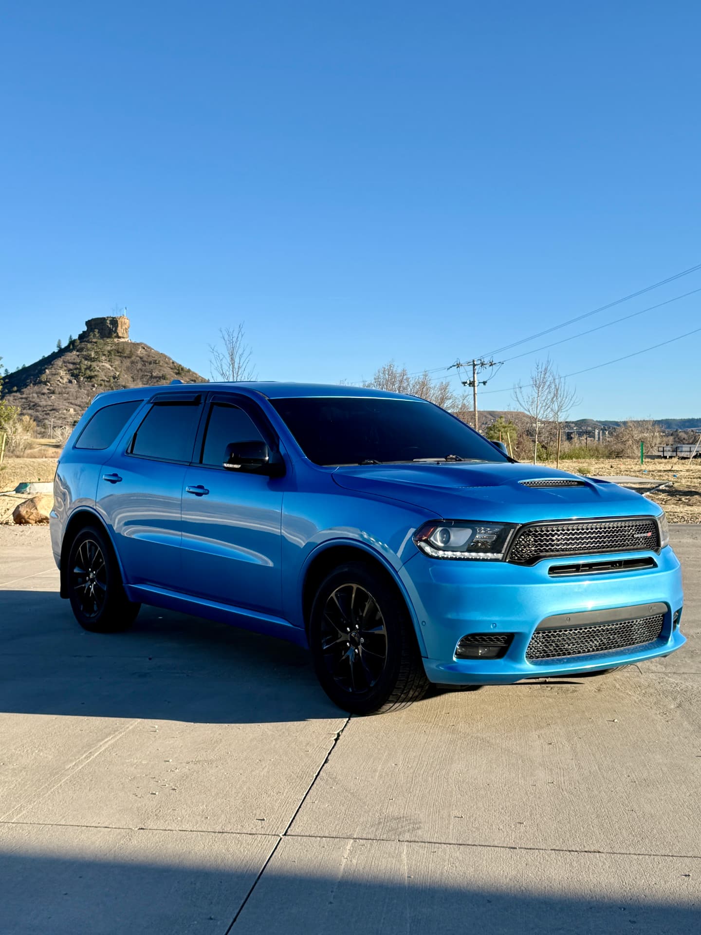 Blue Dodge Durango with ceramic tint parked below Castle Rock