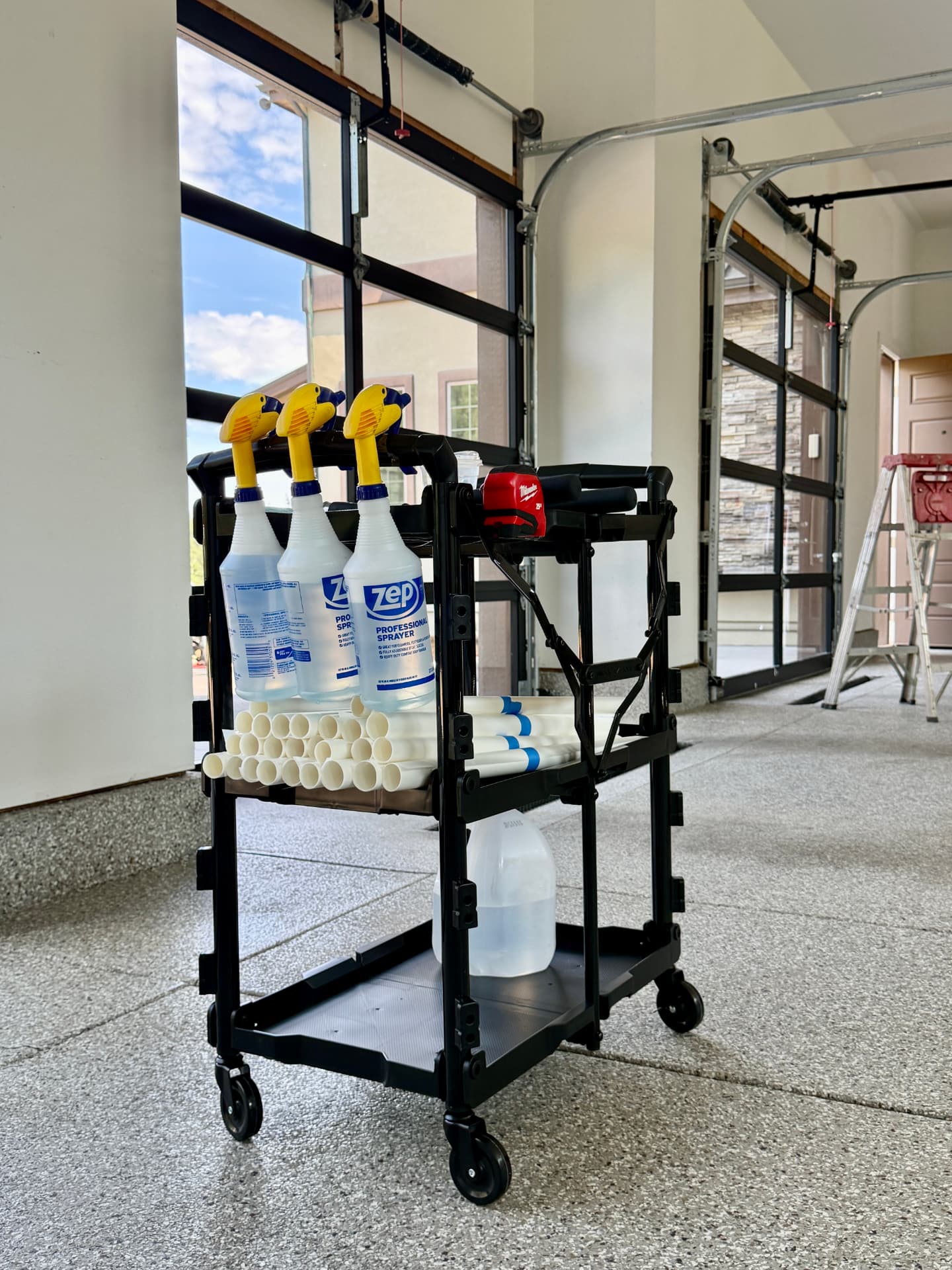 Hypershade film installation cart with sprayers and film rolls staged at a residential garage job site