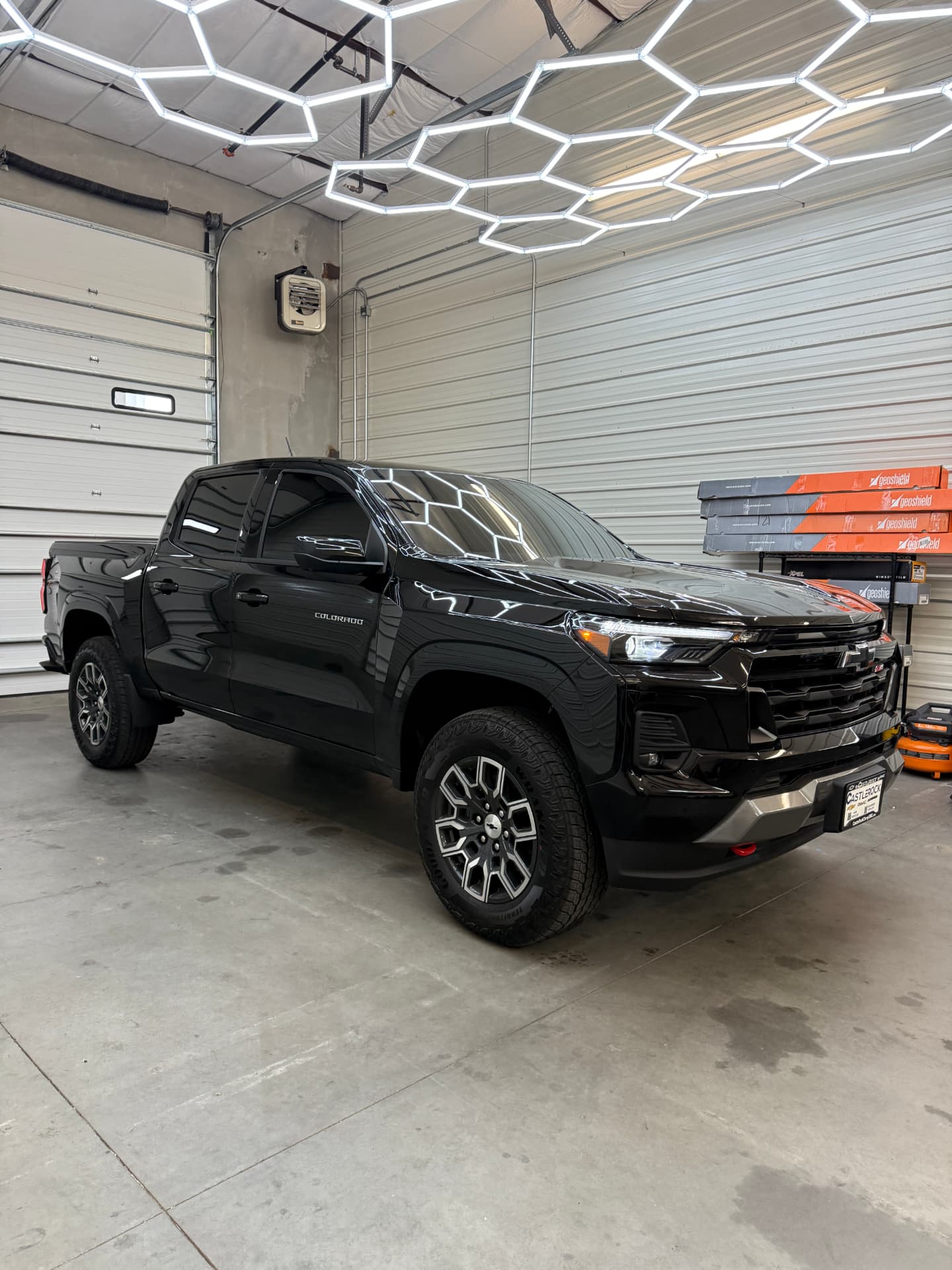 Black Chevrolet Colorado Z71 with ceramic window tint under the shop's hex lighting
